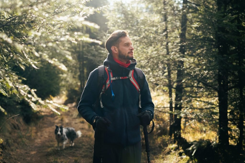 Man in a forest and a fox watching behind him