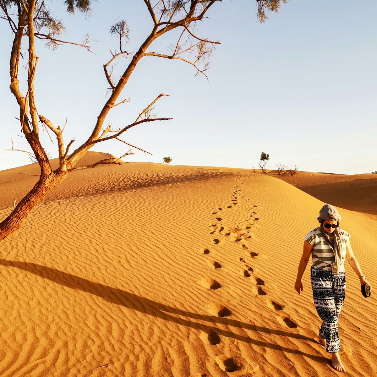 woman walking in brown sand dune leaving footprints in sand, embrace chaos