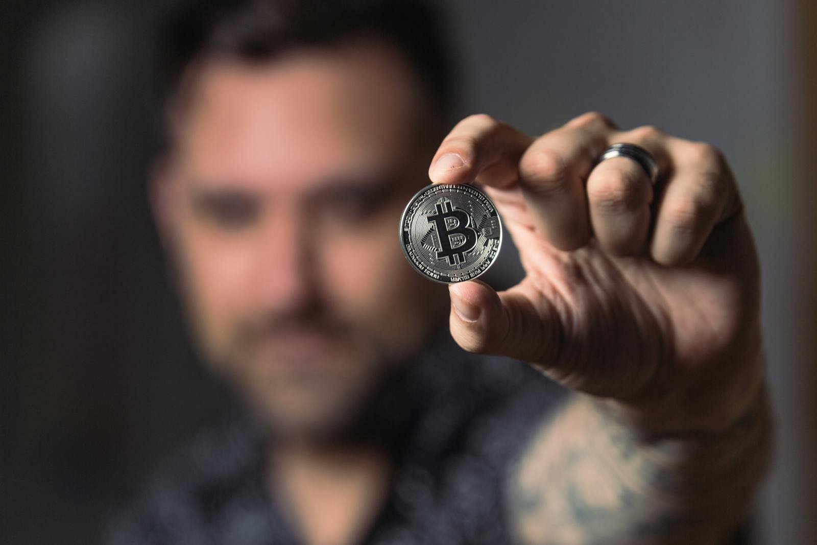 Adult male hand holding a Bitcoin, showcasing cryptocurrency focus indoors. crypto and stocks